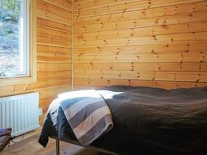 A wooden cabin room with a bed, a window, and a radiator. - 4 Person Holiday Home in Vesterlanda-by Traum (Västerlanda)