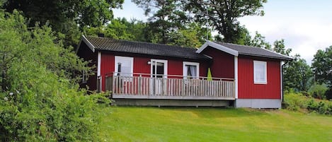 A red building with a porch, surrounded by greenery.