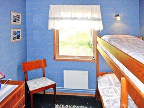 A bedroom with a bunk bed, a chair, a desk, a radiator, and a window with a curtain. - 4 Person Holiday Home in Henan (Henån)