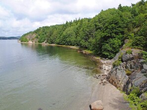 A natural landscape with a calm body of water, a rocky shoreline, and dense greenery. - 4 Person Holiday Home in Henan (Henån)