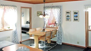 A room with a dining table, chairs, a sofa, a bed, and a window with curtains. - 4 Person Holiday Home in Henan (Henån)
