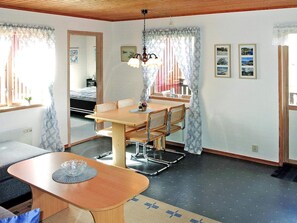 A room with a dining table, chairs, a sofa, a bed, and a window with curtains. - 4 Person Holiday Home in Henan (Henån)