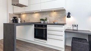 Una cocina moderna con horno empotrado, cafetera y una pequeña isla con pileta.