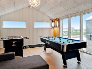 A pool table with a dartboard and a foosball table in a room with large windows. - 5 Star Holiday Home in Lokken (Lokken)