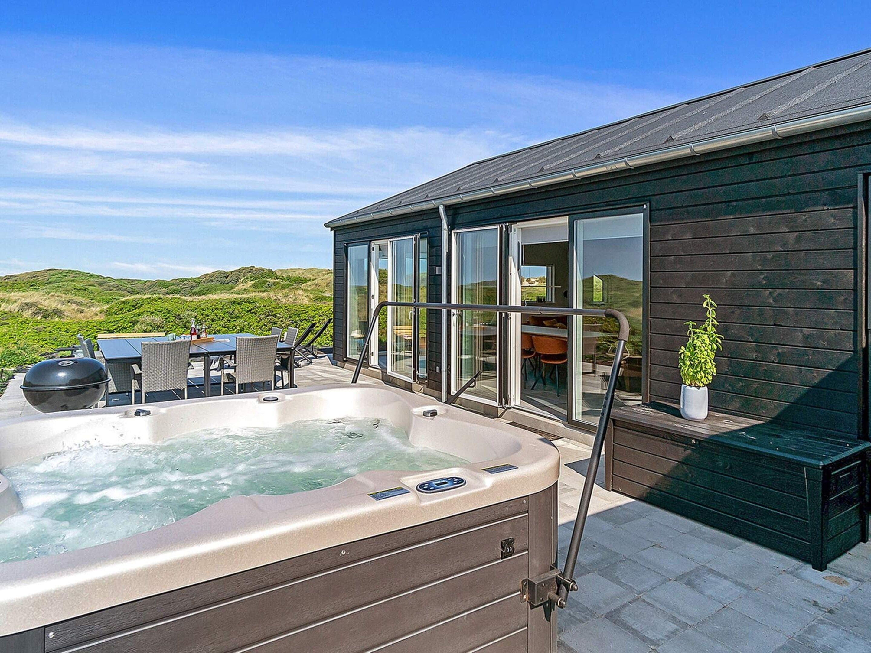 A hot tub with a table and chairs, a potted plant, and a view of the landscape.