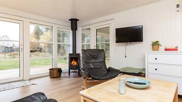A modern living room with a fireplace, a leather chair, a wooden table, and a TV mounted on the wall.