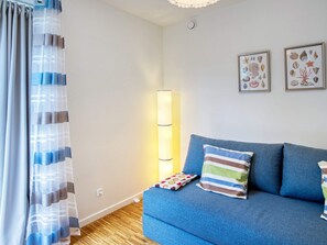 A living room with a blue sofa, striped pillows, a patterned throw, and framed artwork on the wall.