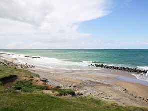 Un paysage côtier avec une rive rocheuse, des vagues et un ciel dégagé.