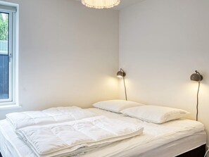 A bedroom with a bed, two wall-mounted lamps, and a window.