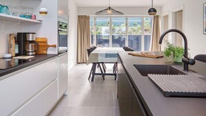 A modern kitchen with a dining area, large windows, and a view of the outdoors. - 6 Person Holiday Home in Gilleleje (Gilleleje)