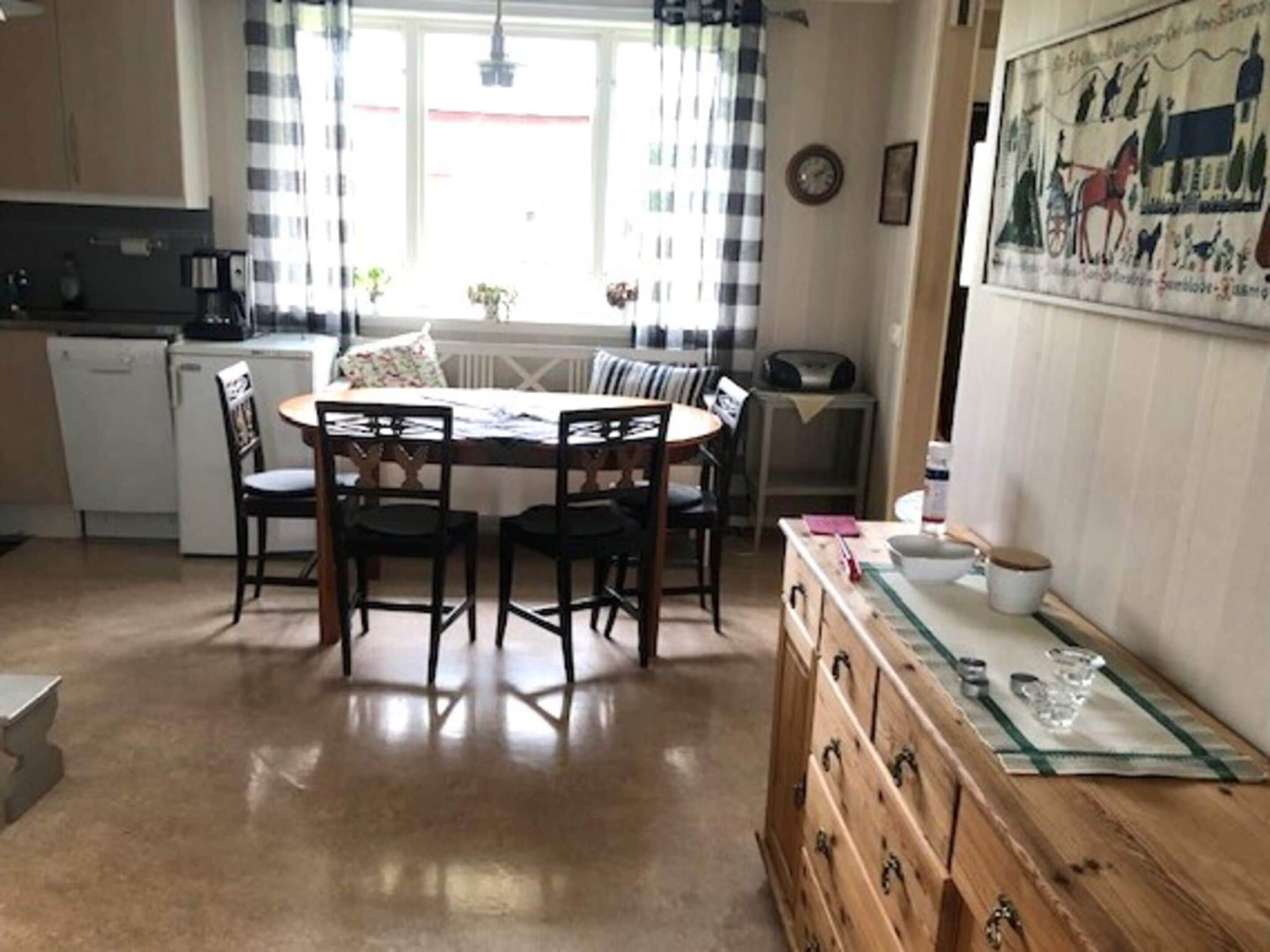 Una cocina compacta con una mesa de comedor, sillas y un aparador de madera con cajones.