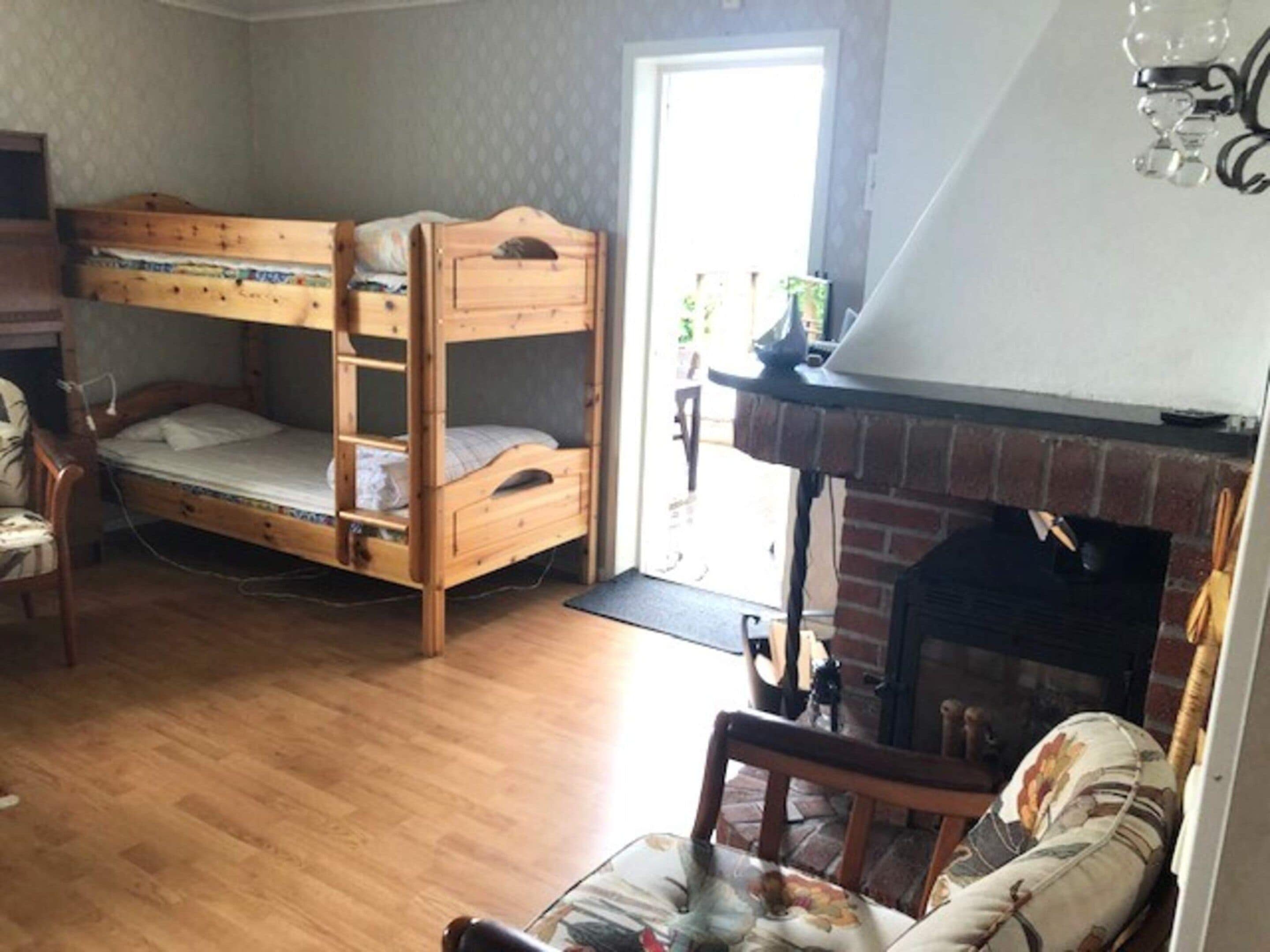 Una habitación con una cama litera, chimenea y una silla.