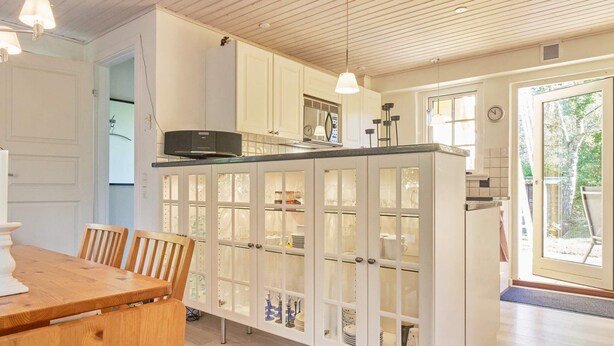 A modern kitchen with white cabinetry, a wooden dining table, and pendant lighting. - 5 Person Holiday Home in Nexo-by Traum (Nexø)