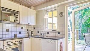 A compact kitchen with white cabinets, a built-in oven, a dishwasher, and a window providing natural light. - 5 Person Holiday Home in Nexo-by Traum (Nexø)