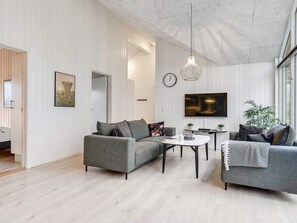 A modern living room with a grey sofa, a coffee table, and a TV. - 5 Star Holiday Home in Vaeggerlose (Vaeggerlose)