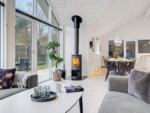 A modern living room with a fireplace, a dining area, and large windows.