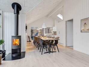 A modern kitchen with white cabinets, a central island, and a built-in wood stove. - 5 Star Holiday Home in Vaeggerlose (Vaeggerlose)