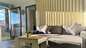 En moderne stue med en hjørnesofa, et træbord og en potteplante.