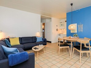 A modern living room with a sofa, coffee table, and dining area with chairs and a table. - 4 Person Holiday Home in Lokken (Lokken)