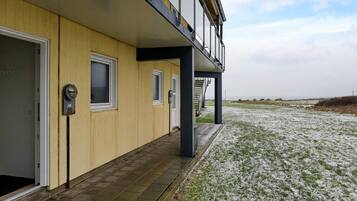 A building with a wooden facade, a covered outdoor area, and a view of a snowy landscape.