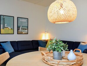 A round dining table with a woven placemat, a potted plant, and a decorative vase. - 4 Person Holiday Home in Lokken (Lokken)