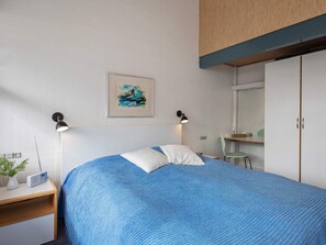 Une chambre à coucher avec un lit, des lampes de chevet, un tableau, une chaise et une armoire.