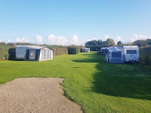 A campsite with several caravans and a small building, likely a communal area, set in a grassy field with a clear sky. - 4 Star Holiday Home in Vaeggerlose (Vaeggerlose)