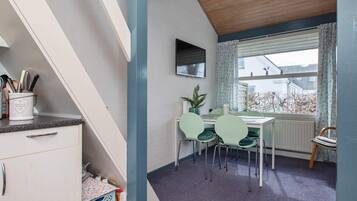 A dining area with a table, chairs, and a window with curtains.
