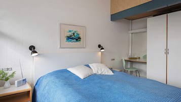 Un dormitorio con cama, lámparas de noche, un cuadro, una silla y un armario.