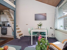 Et moderne køkken med komfur, ovn og vask, et spiseområde med bord og stole, samt en trappe.