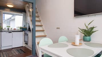 Una cocina moderna con armarios blancos, estufa integrada y ventana con vista a la calle.