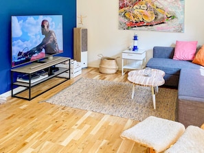 A living room with a television, a blue wall, a painting, a sofa, and a coffee table. - 5 Star Holiday Home in Klovedal (Klovedal)