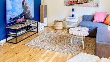 A living room with a television, a blue sofa, a coffee table, and a rug.