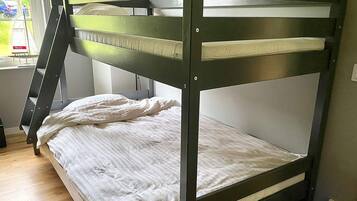 Un letto a castello con una scala, una finestra vista strada e una presa elettrica sul muro.