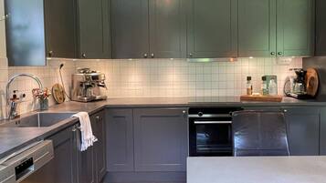 Una cocina moderna con gabinetes grises, un lavamanos de acero inoxidable, una cafetera y una encimera de madera.