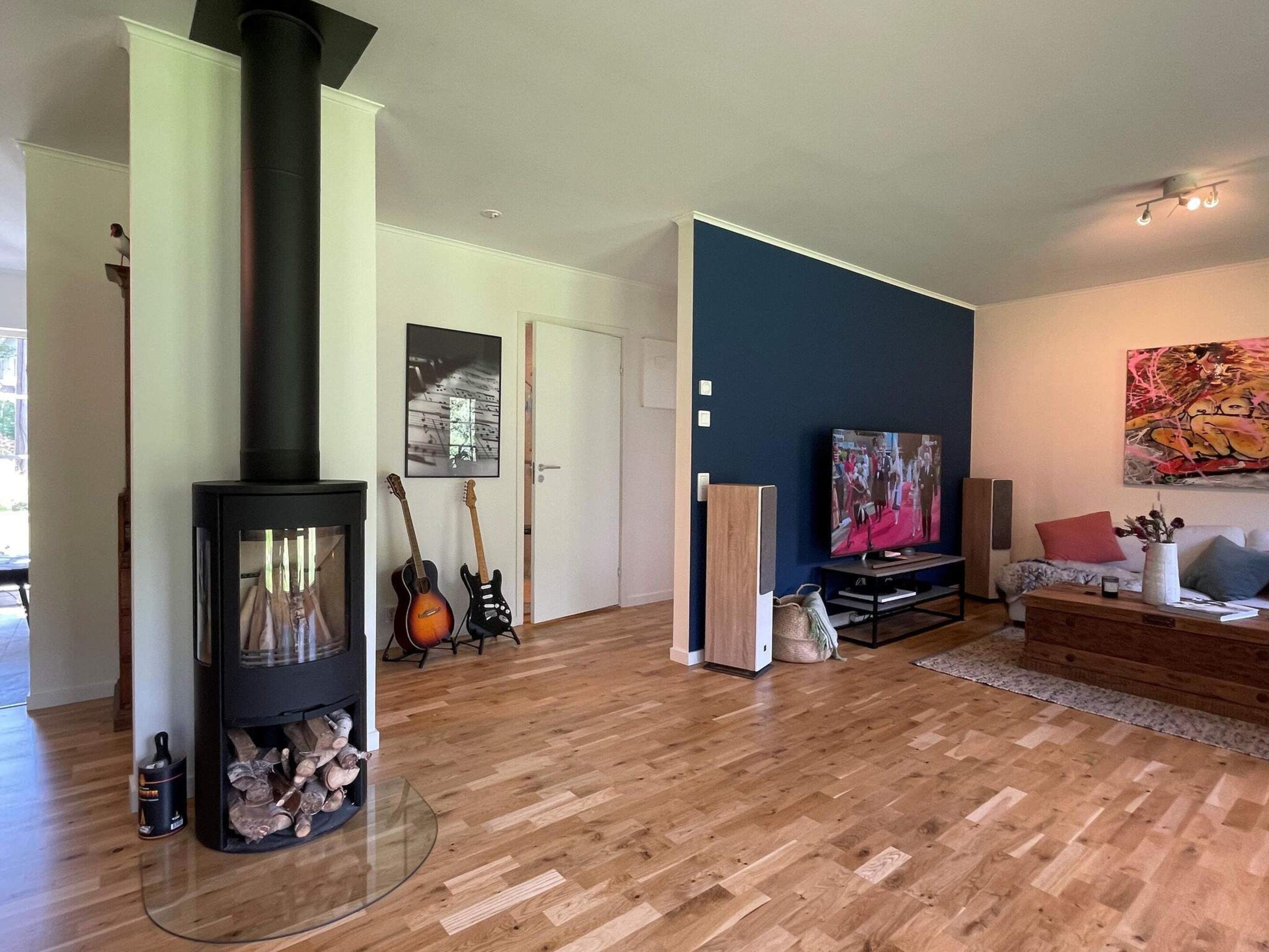 A modern living room with a wood-burning stove, a television, and a sofa.