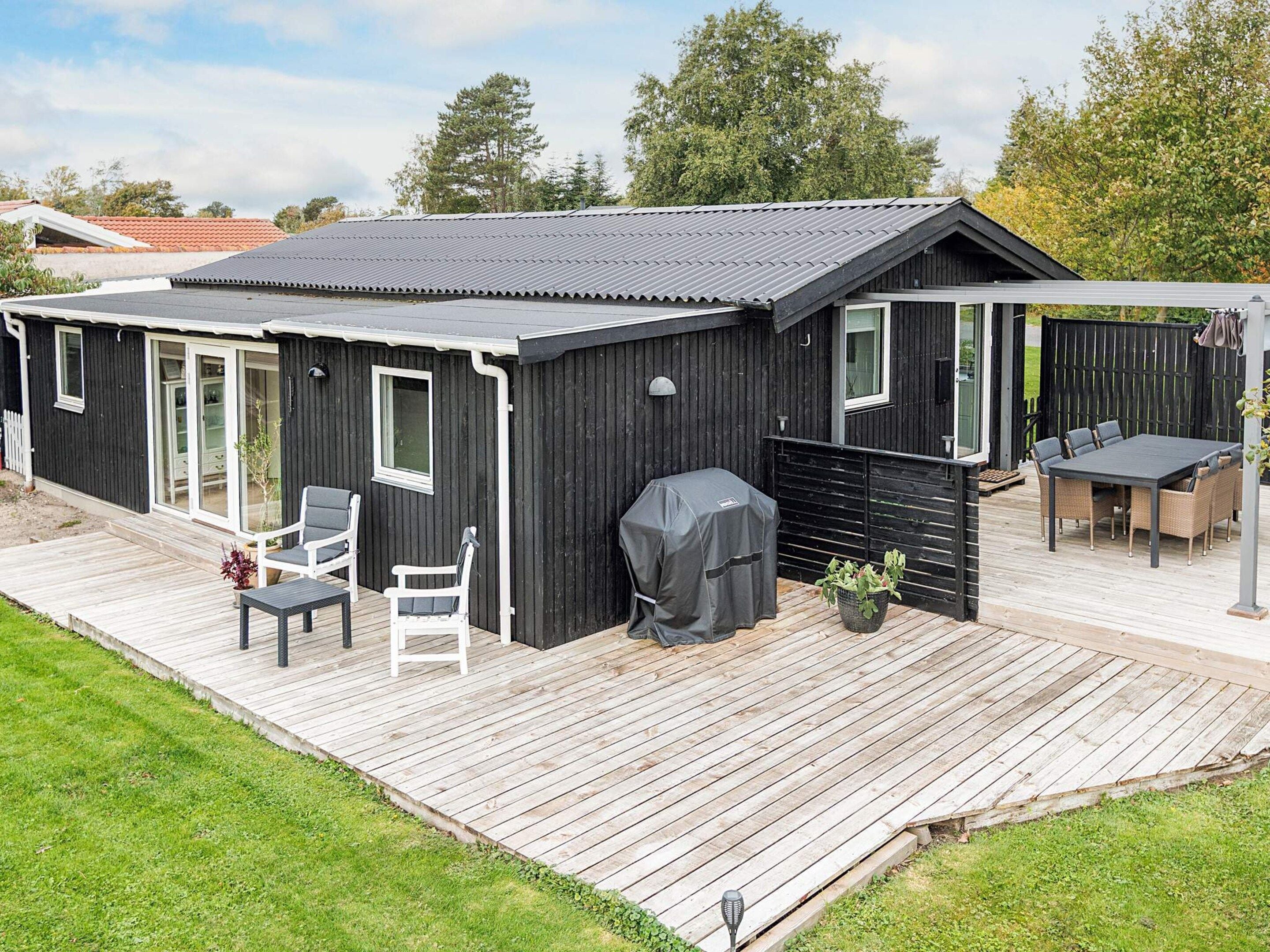 En moderne terrasse med grill, siddepladser og en overdækket patio.