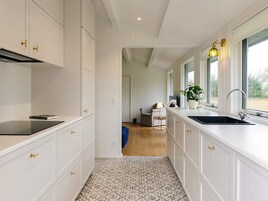 Una cocina moderna con armarios blancos, encimera negra y suelo estampado.