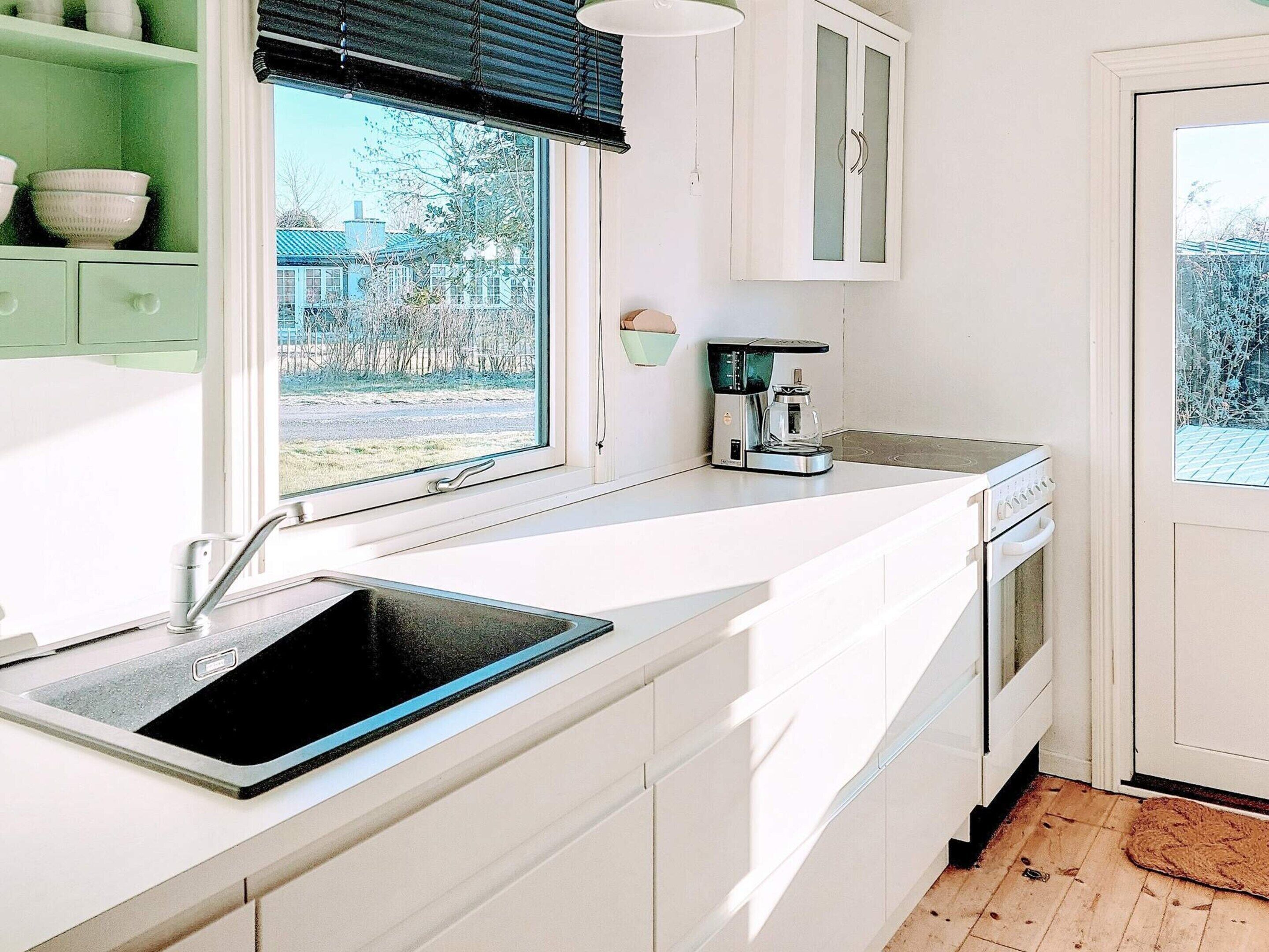 Een moderne keuken met een ingebouwd spoelbakje, een koffiezetapparaat en uitzicht op buiten.
