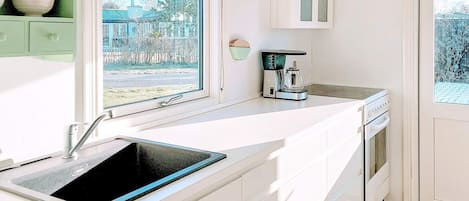 A modern kitchen with a built-in sink, a coffee maker, and a view of the outside.