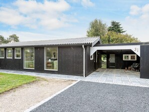 Ein modernes Gebäude mit schwarzer Fassade, großen Fenstern und einem Schotterweg.
