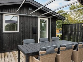 Un espacio de patio exterior con terraza de madera, una mesa con sillas y vistas a un paisaje verde.