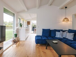 A modern living room with a blue sofa, a black coffee table, and a TV on the left.