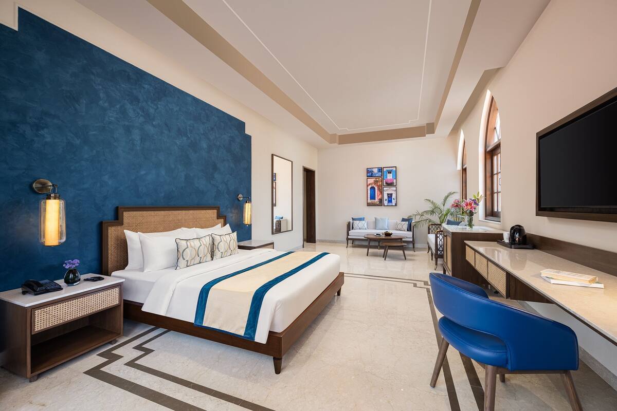 A hotel room with a bed, desk, chair, and a television.