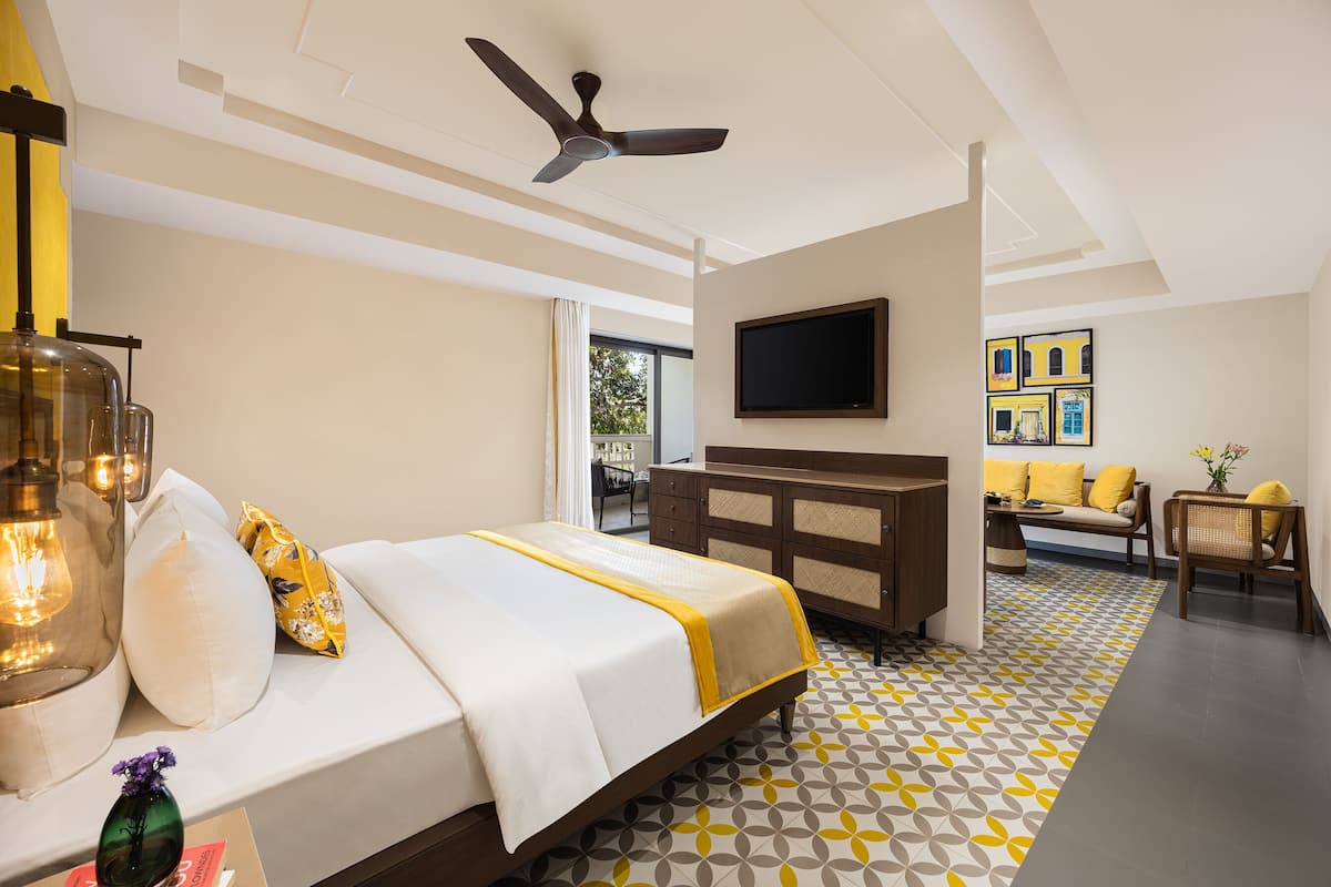 A hotel room with a bed, a TV mounted on the wall, a ceiling fan, and a patterned floor.