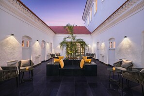 A spacious indoor area with a central seating area, surrounded by walls with decorative moldings and a tiled floor. - The Yellow House, Goa – IHCL SeleQtions (Anjuna)