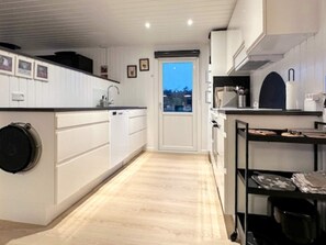 A modern kitchen with white cabinetry, a built-in oven, and a view through a door to the outside.