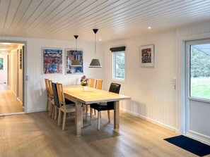 A dining area with a wooden table, chairs, pendant lights, and framed artwork on the walls.
