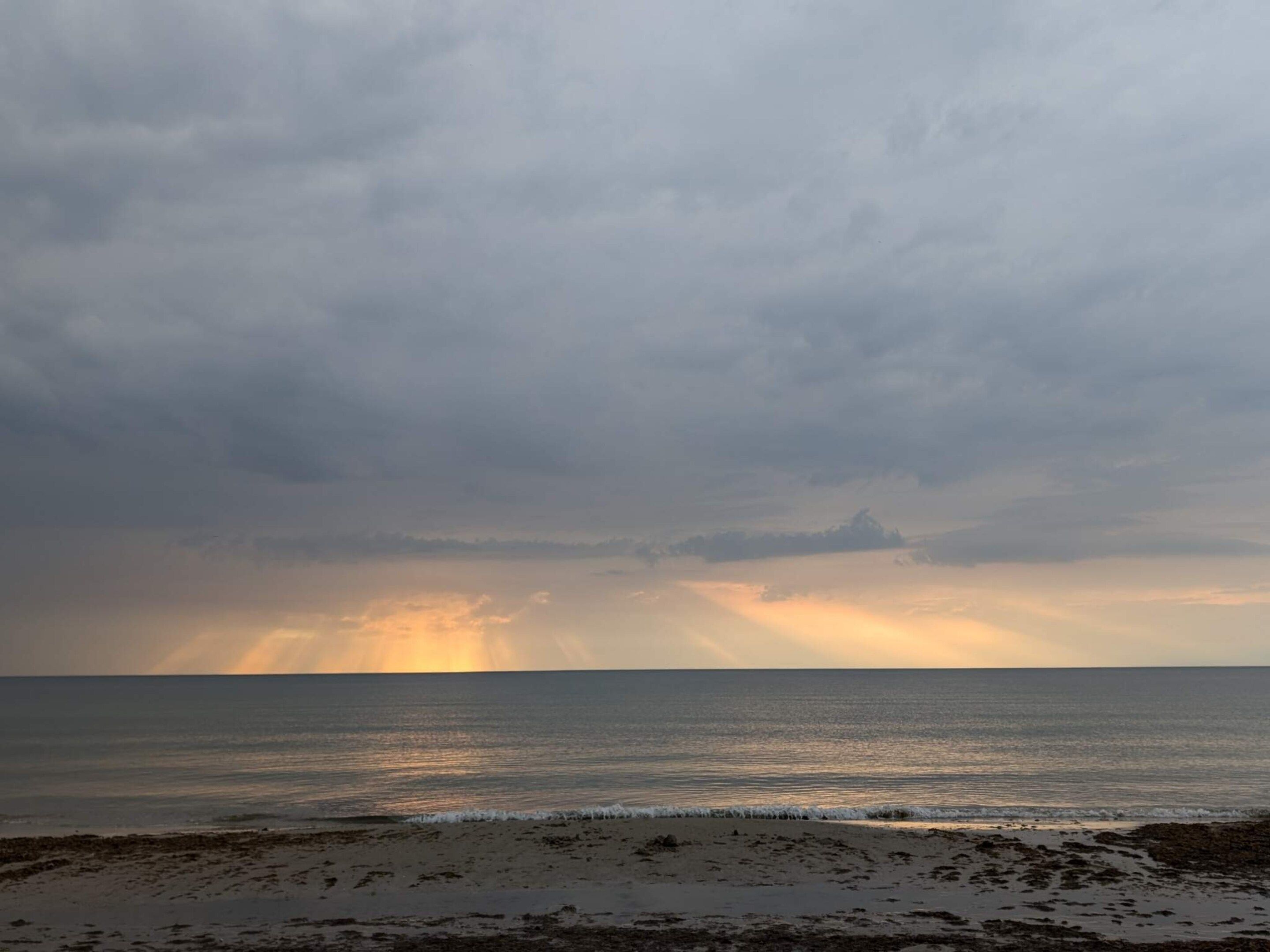 Ein Strand mit Blick auf den Ozean und einem bewölkten Himmel.