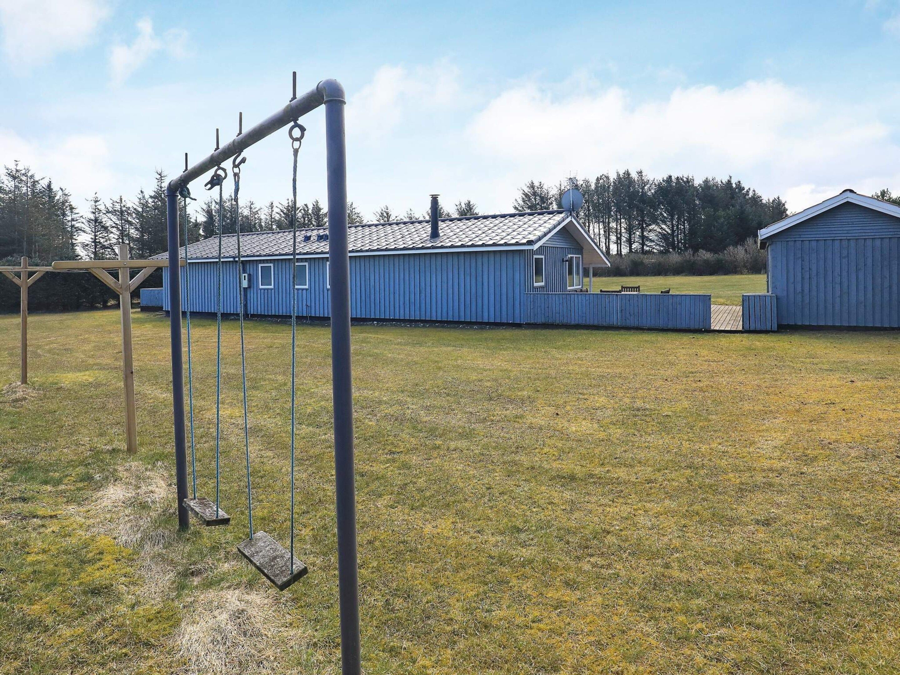 Un terrain de jeux avec des balançoires et un bâtiment bleu en arrière-plan.